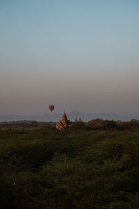 Sunrise in bagan. hot air balloon flying next to a pagoda.