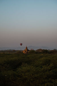 Hot air balloons on field against sky during sunset