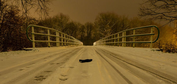 Road passing through snow covered bridge during winter