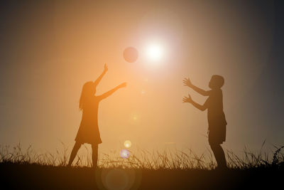 Silhouette people with arms raised at sunset