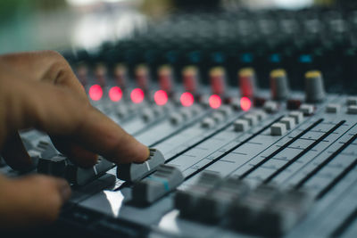 Close-up of human hand adjusting sound mixer in nightclub