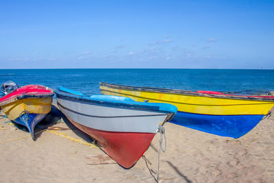 Deck chairs on beach against blue sky