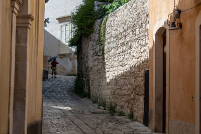 An old man with an umbrella at the end of the street