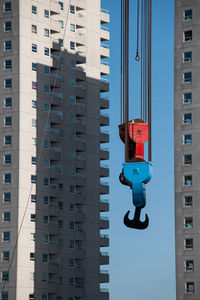Low angle view of crane against buildings