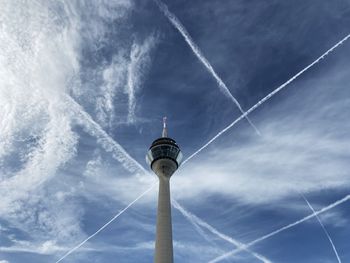 Low angle view of communications tower against cloudy sky