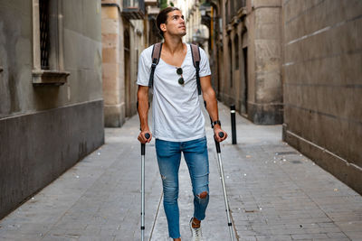 Young latin man with crutches visiting the city
