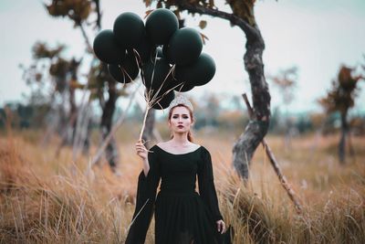 Portrait of woman with balloons standing on field