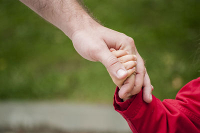Cropped image of father holding daughter hand