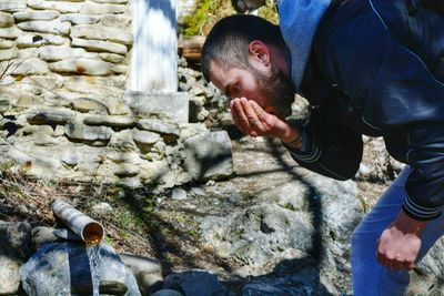 Man drinking water flowing from pipe