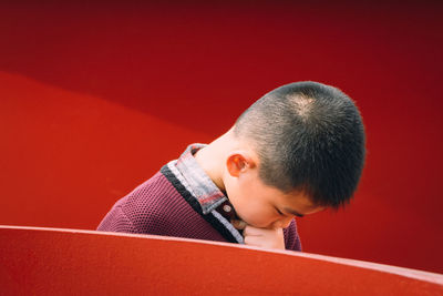 Portrait of boy looking away against red wall