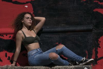 Young woman sitting against graffiti