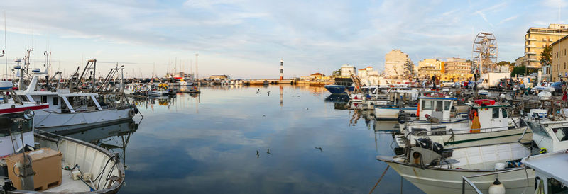  the port of cattolica with the boats and the lighthouse reflecting in the water at sunset