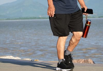 Low section of man standing on beach