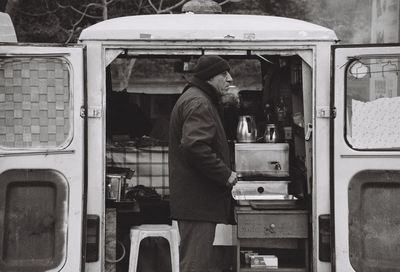Side view of man selling drink while standing by vehicle