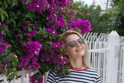 Portrait of smiling woman wearing sunglasses standing by plants