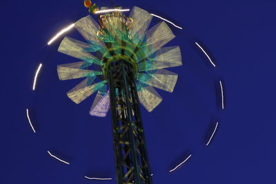Blurred motion of chain swing ride against clear sky at night