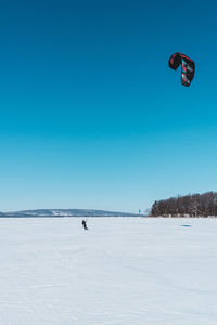 Snow covered landscape against clear blue sky