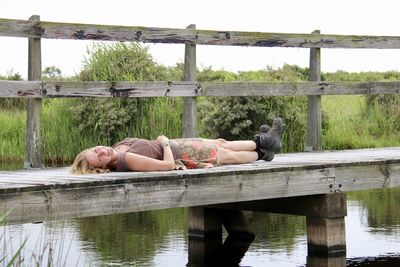 Young woman relaxing on wood by lake