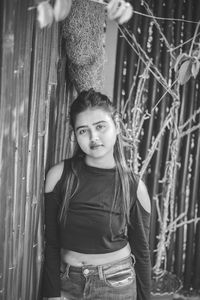 Portrait of a young woman standing against plants
