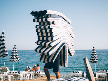 Person carrying cushions on beach