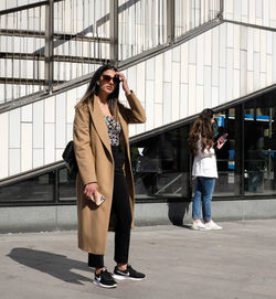 Full length portrait of woman standing against bus