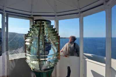 Rear view of man sitting by window against sea