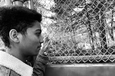 Side view of young man looking through window