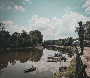 Man standing by lake against sky