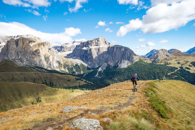 Rear view of man walking on mountains against sky