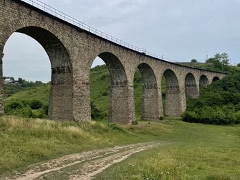 Arch bridge on field against sky