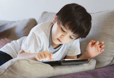 Rear view of boy relaxing on sofa at home