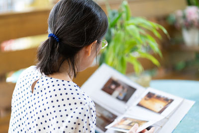 Senior asian woman looking at photo album to remind of old happy memory