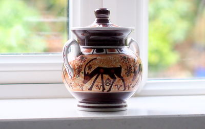 Close-up of teapot on window sill on table