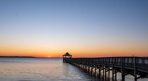 Pier over sea against sky during sunset