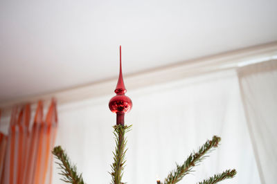 Decorated christmas tree in front of blurred room with orange curtains unusual perspective.