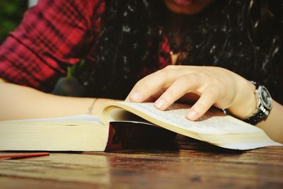 Midsection of woman reading book on table