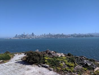 Scenic view of sea and buildings against clear blue sky