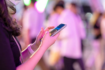 Woman using her mobile phone in the street, night light background