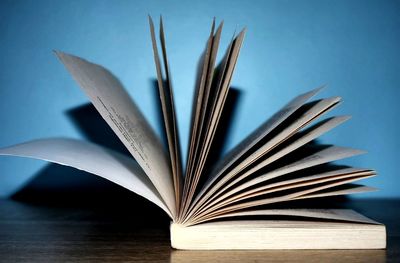 Close-up of open book on table against blue background