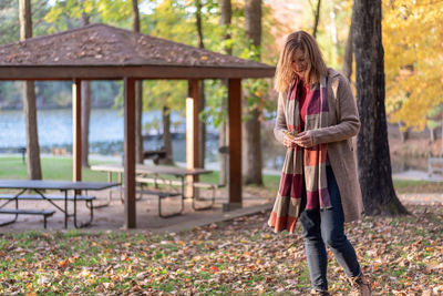 Full length of woman standing in park during autumn