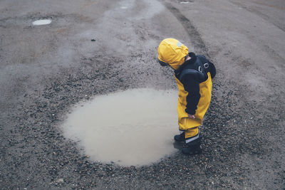 Child standing at puddle
