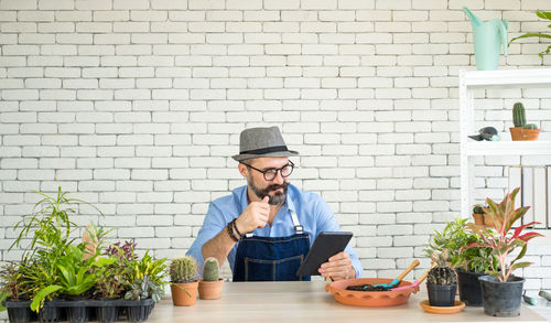 Portrait of young man sitting against brick wall