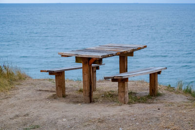 Empty bench on beach by sea