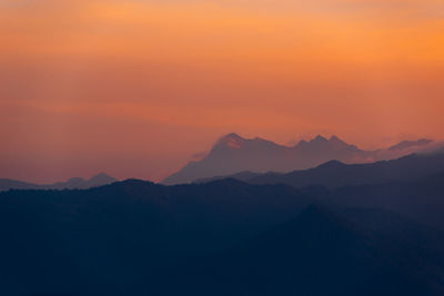 Scenic view of silhouette mountains against romantic sky at sunset