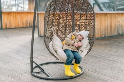 Little girl sat down to rest after a walk in a rattan chair outdoors in a warm autumn, spring. child