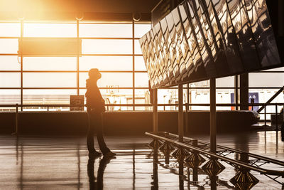 Silhouette man standing by window at airport