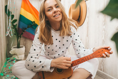 Young millennial hippie woman sitting on balcony play guitar. music lesson and singer sitting. lgbtq 