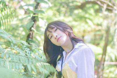 Portrait of young woman standing against plants