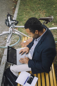 Male professional using laptop while sitting on bench