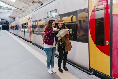 Friends reading map at railroad station platform